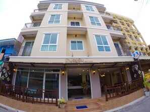 A multi-story hotel with a central entrance, balconies on each floor, and a sign indicating the name. - Baan Yooyen Hua Hin 57 (Hua Hin)
