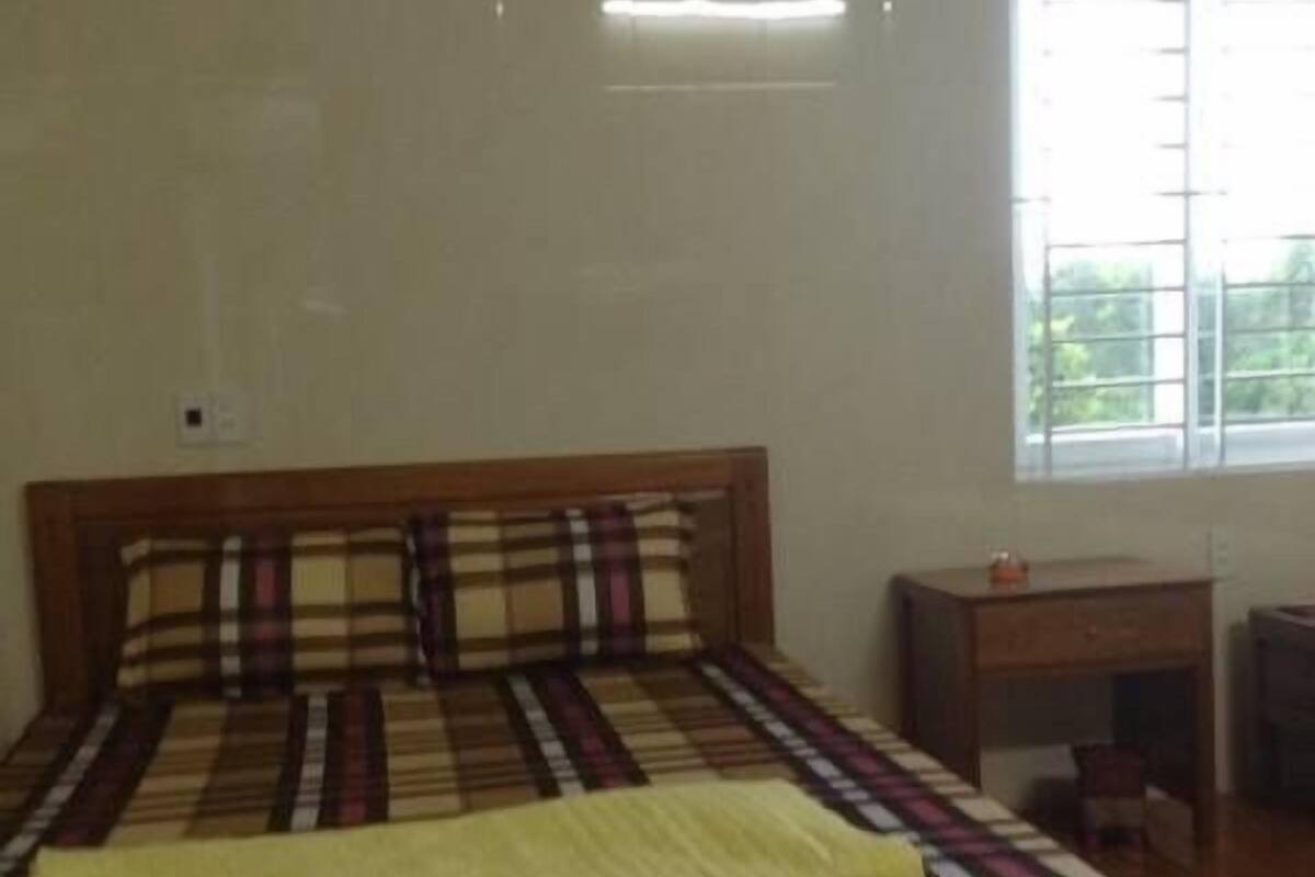 Une chambre à coucher avec un lit en bois, une table de chevet et une fenêtre avec des stores.