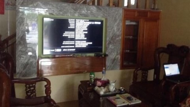 Ein Wohnzimmer mit Fernseher auf einem Marmorsockel, einer Holztreppe und einem Laptop auf einem Tisch.