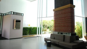 A modern lobby with a large glass window, a seating area, and a decorative pillar. - The Legend Boathouse - 904 (Cha-am)