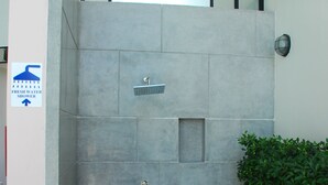 A shower area with a tiled wall, a metal handrail, and a sign indicating a fresh water shower. - The Legend Boathouse - 904 (Cha-am)