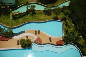 An aerial view of a resort with a large swimming pool, surrounded by palm trees and greenery. - The Legend Boathouse - 904 (Cha-am)