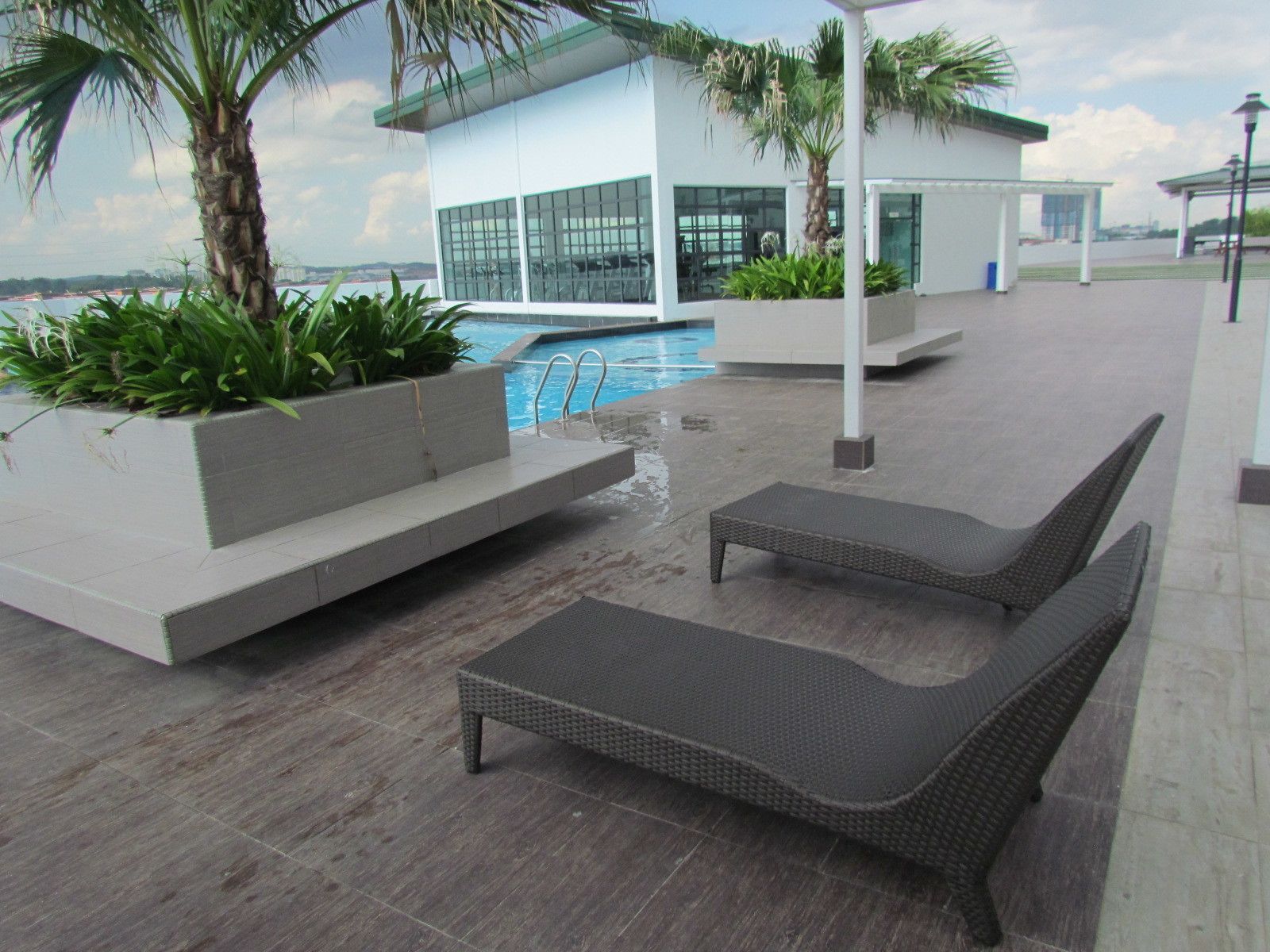 A poolside area with lounge chairs, a pool, and a modern building with large windows.