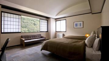 Une chambre d’hôtel moderne avec une grande fenêtre, un canapé, un lit et un bureau.