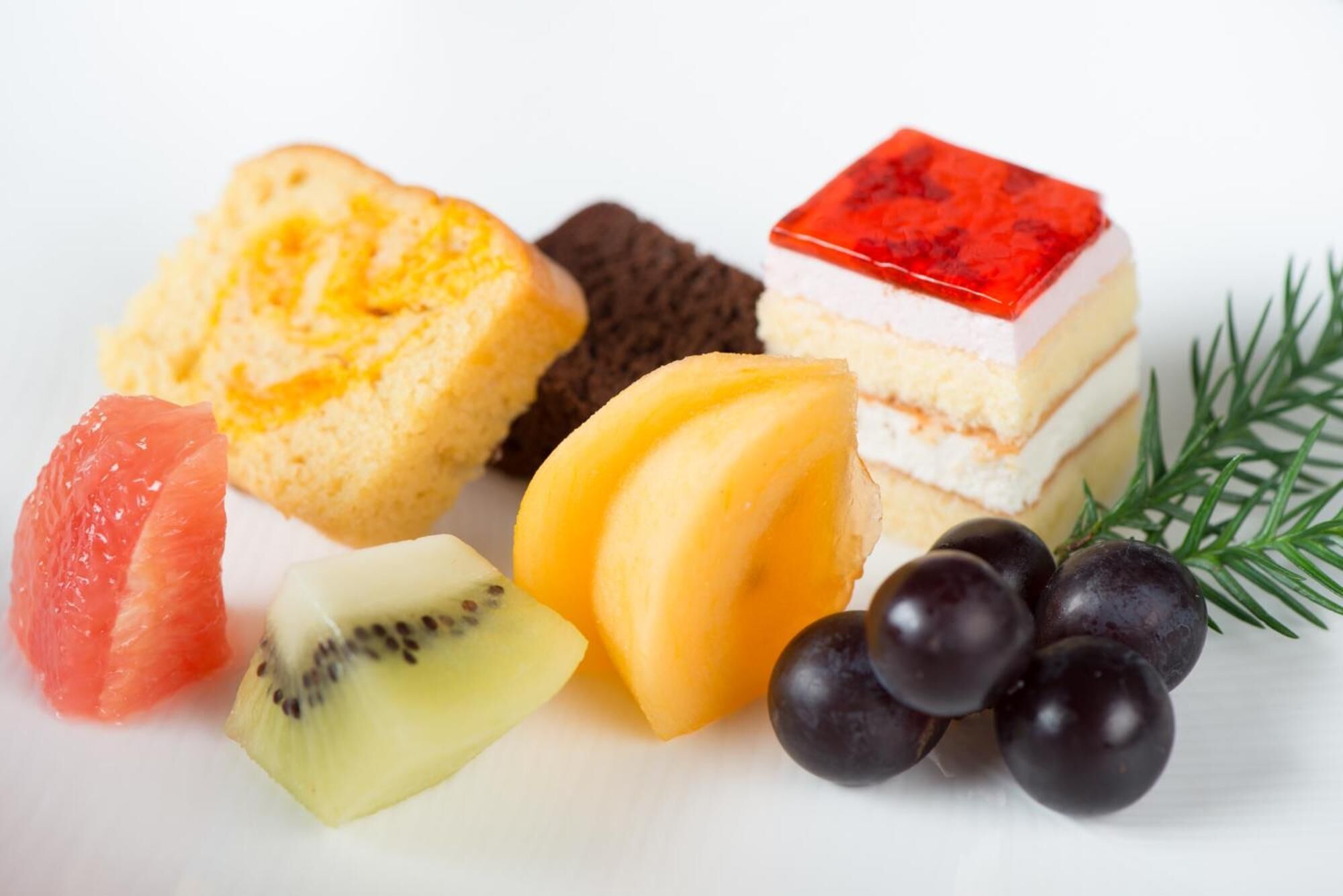 Diversos itens de comida, incluindo doces, frutas e uma sobremesa em camadas.