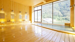 A spacious indoor area with wooden flooring and large windows offering a view of a forested landscape. - Beni (Tozawa)