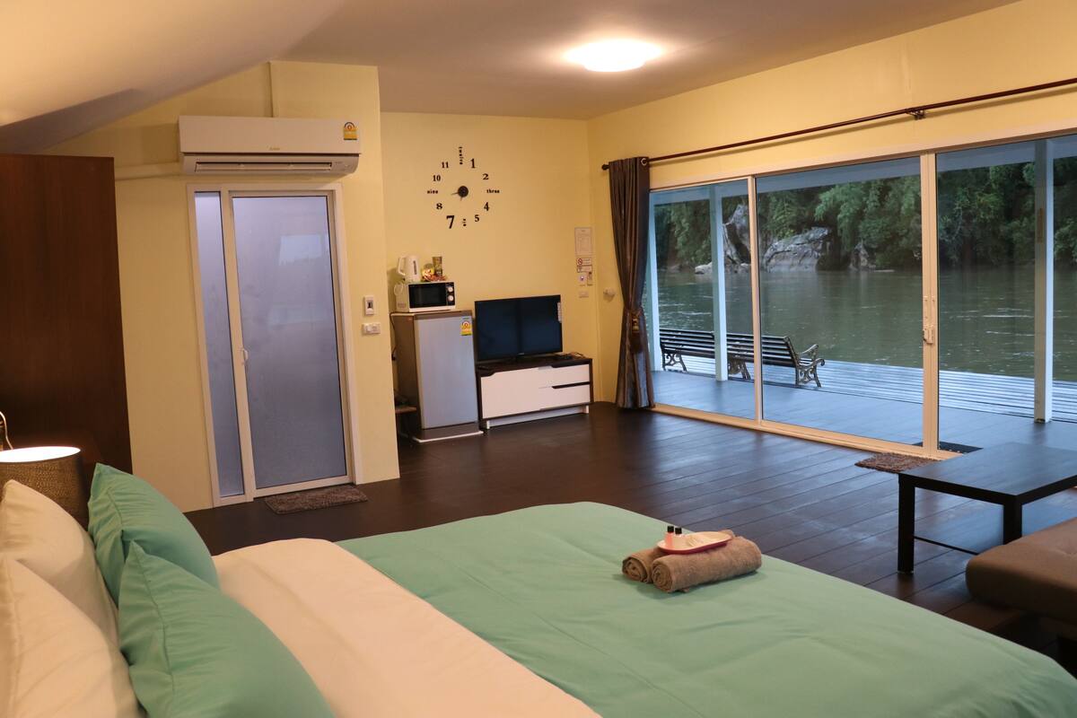Hotelkamer met een bed, bureau, stoel, raam met uitzicht op een wateroppervlak en een airconditioning.
