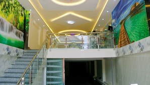 A hotel lobby with a staircase, a mural of a waterfall, and a large painting of a bridge over water. - Yen Vy 32 Hotel - Hostel (Quy Nhon Nam)