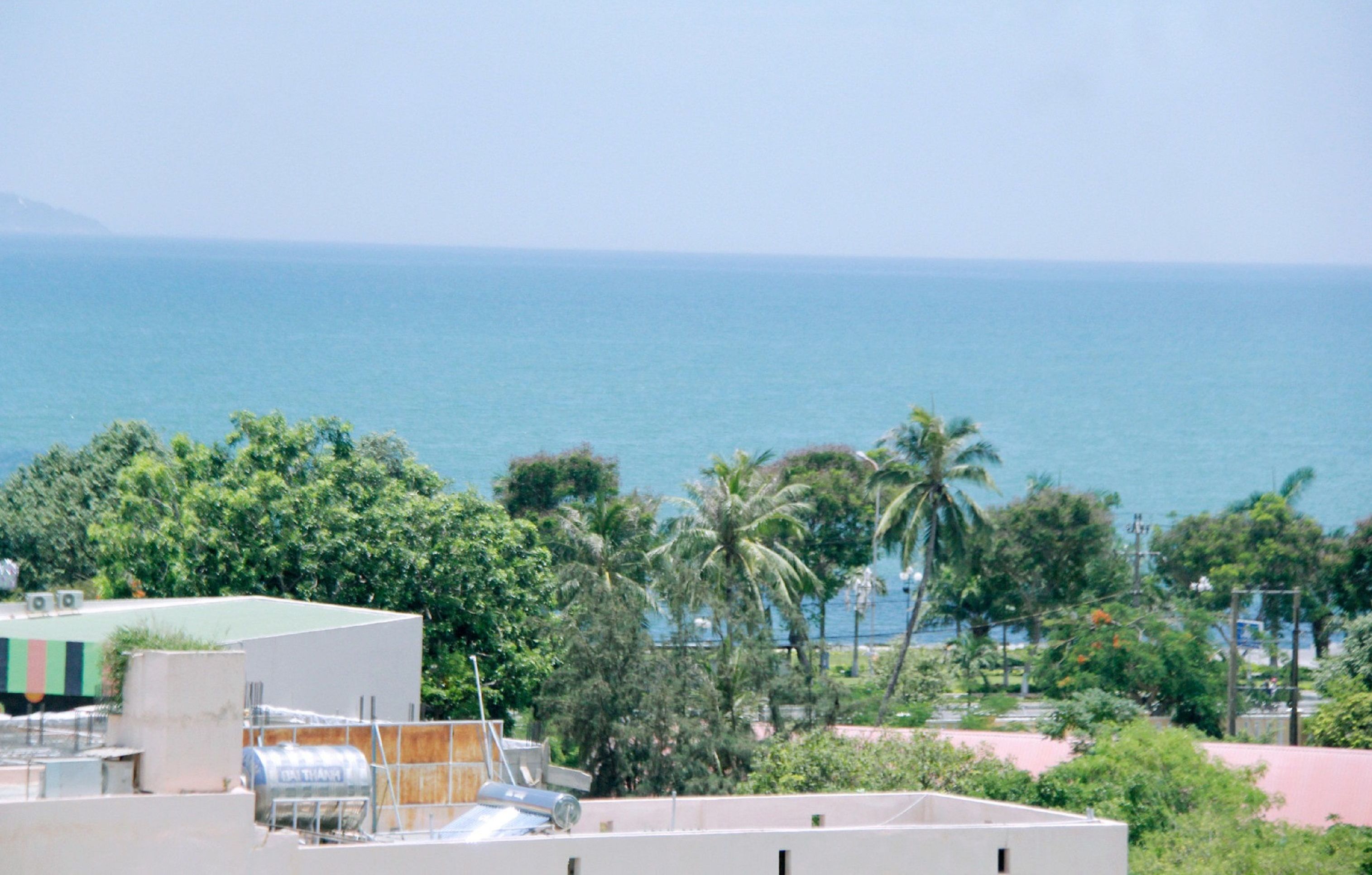 A coastal view with a building, trees, and the sea.