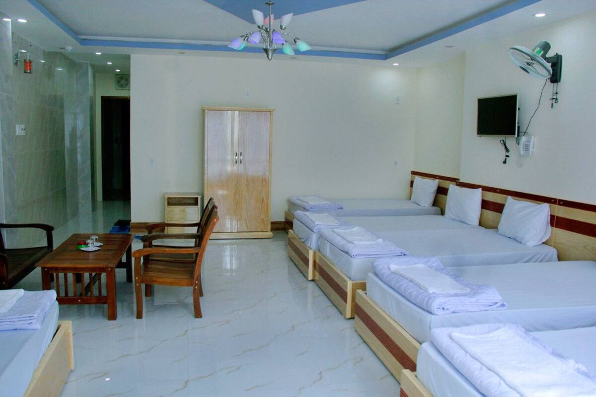 A hotel room with a bed, a desk, a chair, a wardrobe, and a ceiling fan.