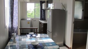 Una cocina compacta con una mesa de vidrio, dos tazones, un tostador y un refrigerador.