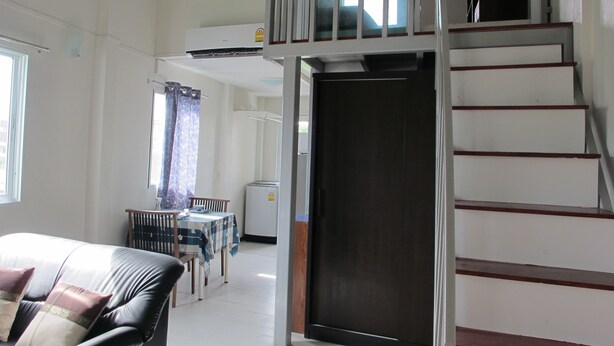 Una habitación de hotel con cama, zona de comedor con mesa y sillas, y una escalera.
