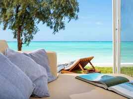 Quarto com vista para o oceano, uma praia e uma árvore.