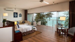 Una habitación de hotel moderna con una cama grande, un balcón con vistas al mar y un ventilador de techo.