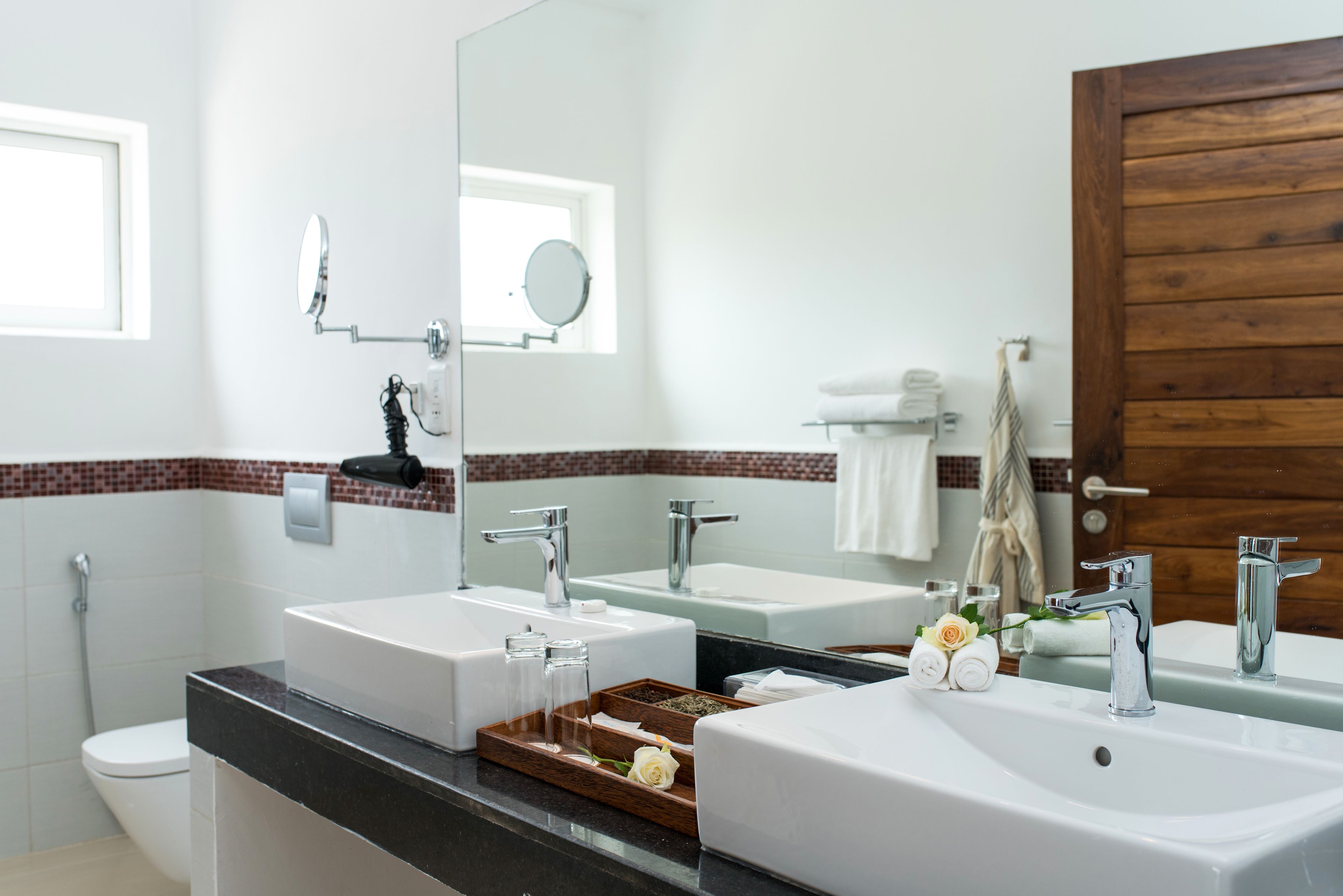 A bathroom with two sinks, a mirror, and a wooden door.