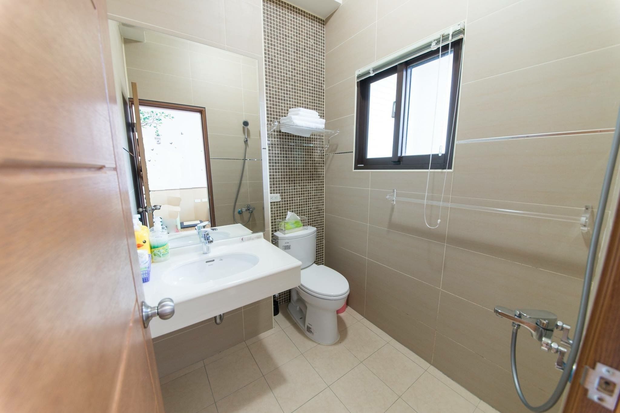 Ein Badezimmer mit Waschbecken, Toilette, Dusche und Fenster.
