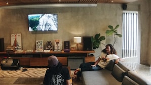 A living room with a sofa, a television, and a bookshelf. - Surf Motel Canggu (Canggu)