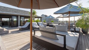 A rooftop deck with outdoor seating, umbrellas, and potted plants. - Surf Motel Canggu (Canggu)