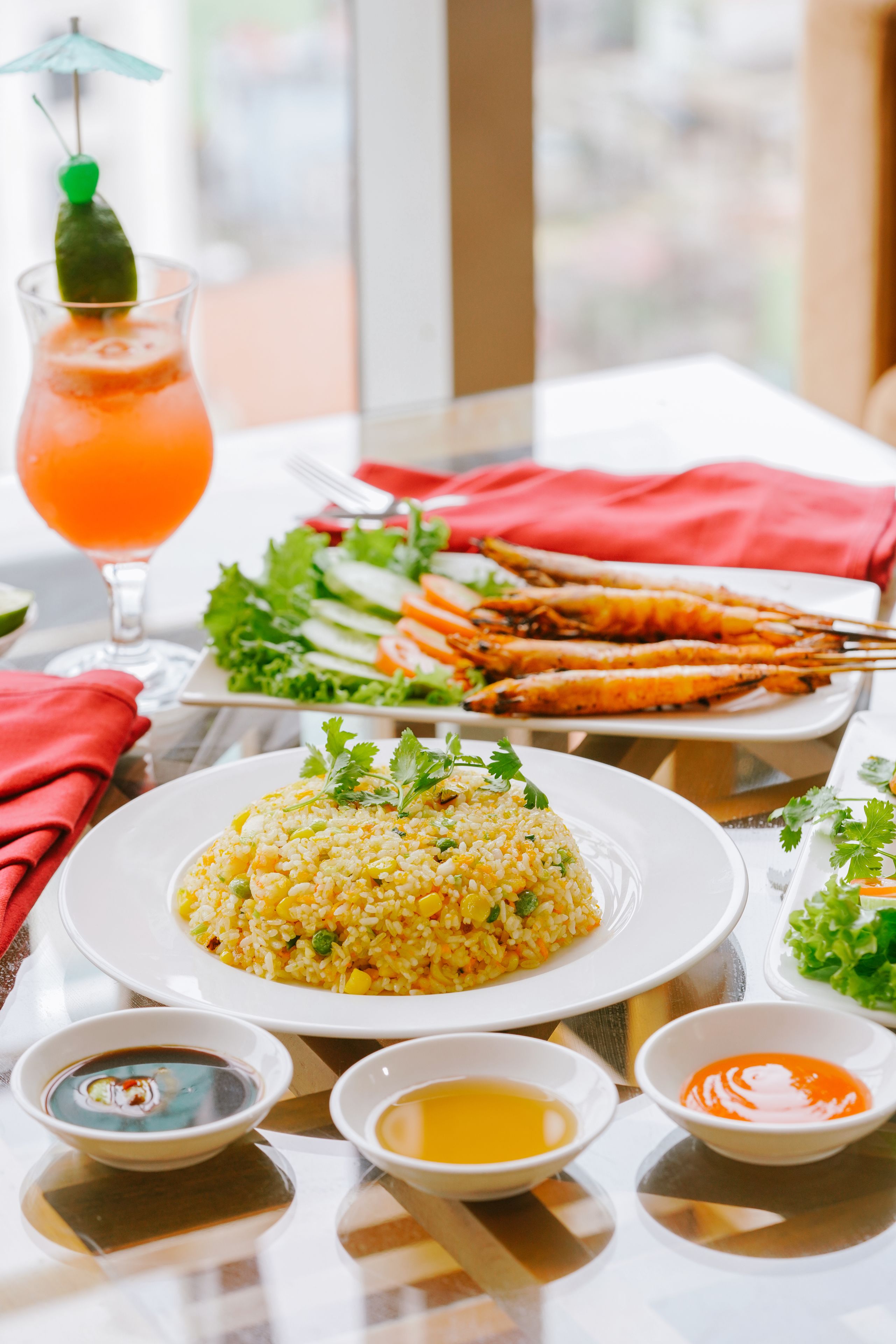A table with a plate of rice, grilled seafood, and various dipping sauces.