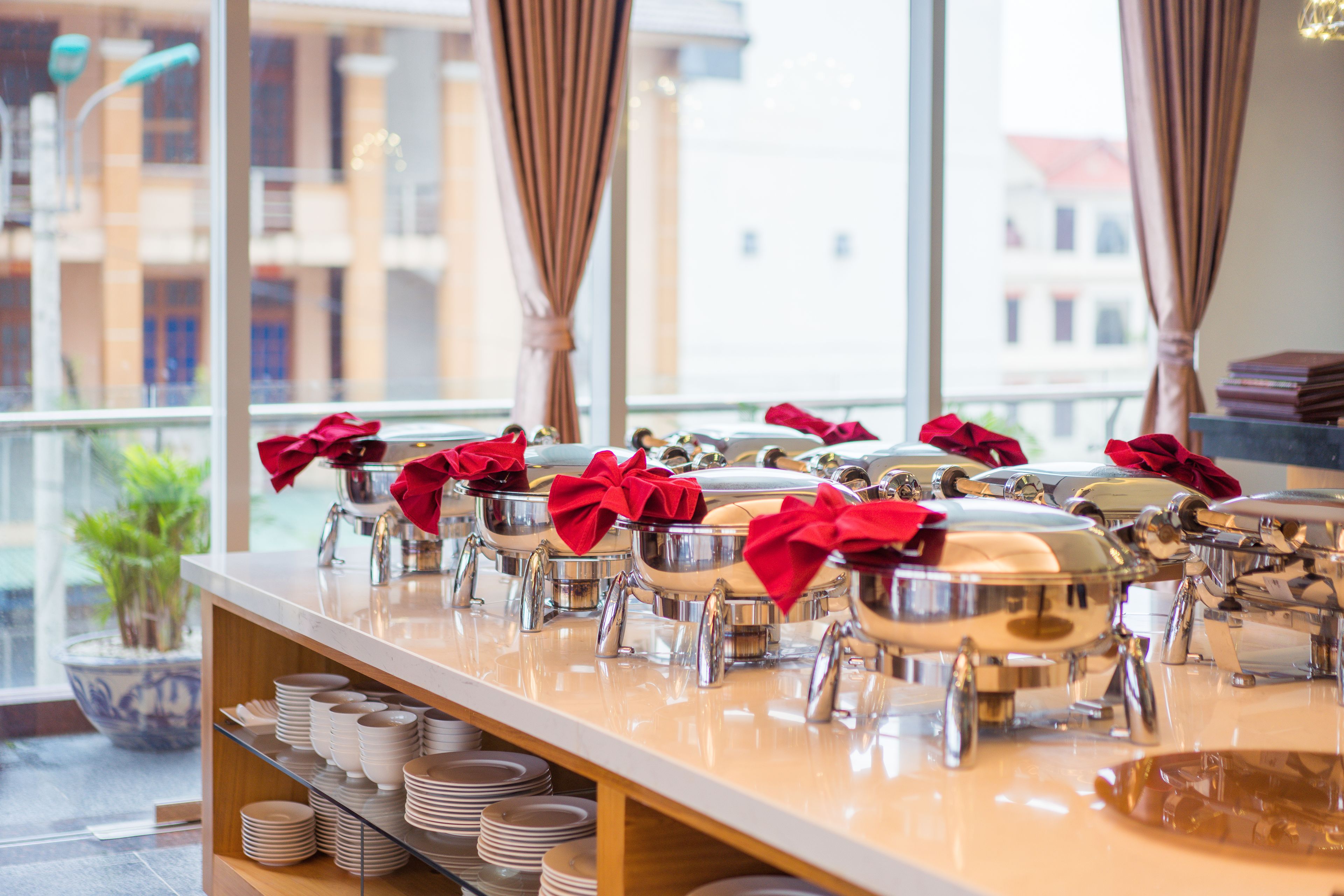 A buffet setup with multiple serving stations, each with a red bow on top, and a variety of dishes and utensils.