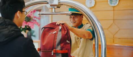 Una persona entregando una mochila roja a un empleado con uniforme en la recepción de un hotel.
