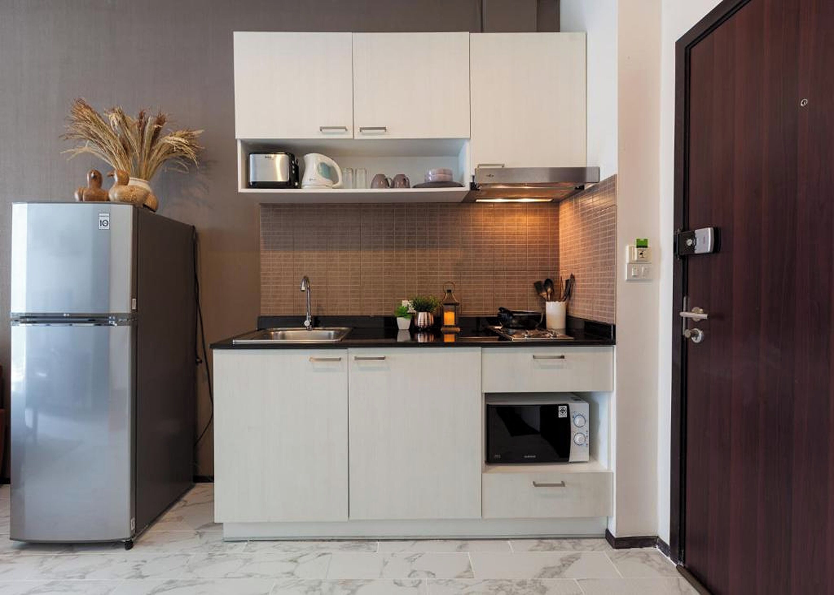 Una cocina compacta equipada con refrigerador, microondas y un lavamanos pequeño.