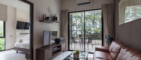 A modern living room with a sofa, coffee table, TV, and a balcony with outdoor furniture.