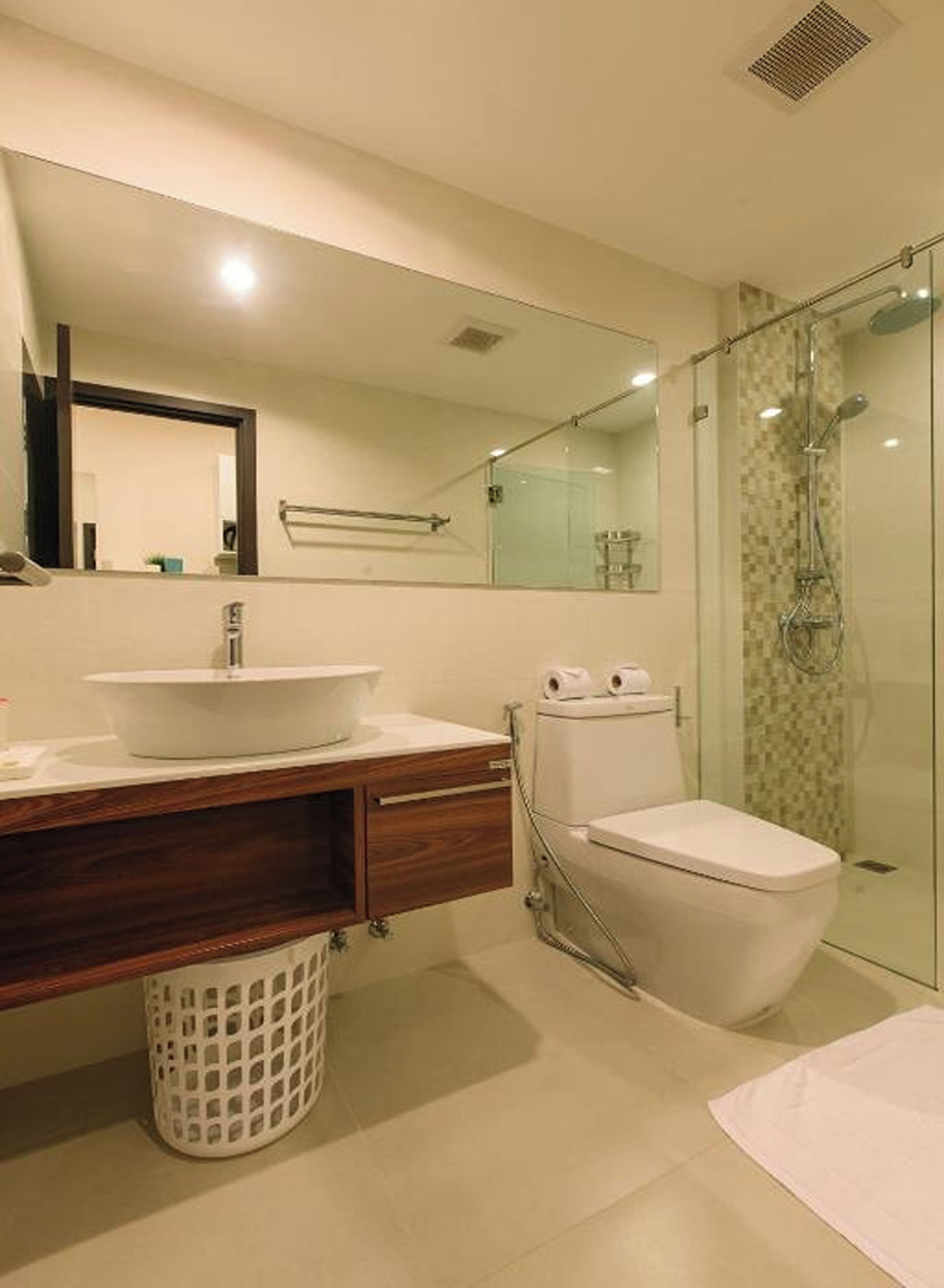 A modern bathroom with a glass-enclosed shower, a white sink, and a toilet.