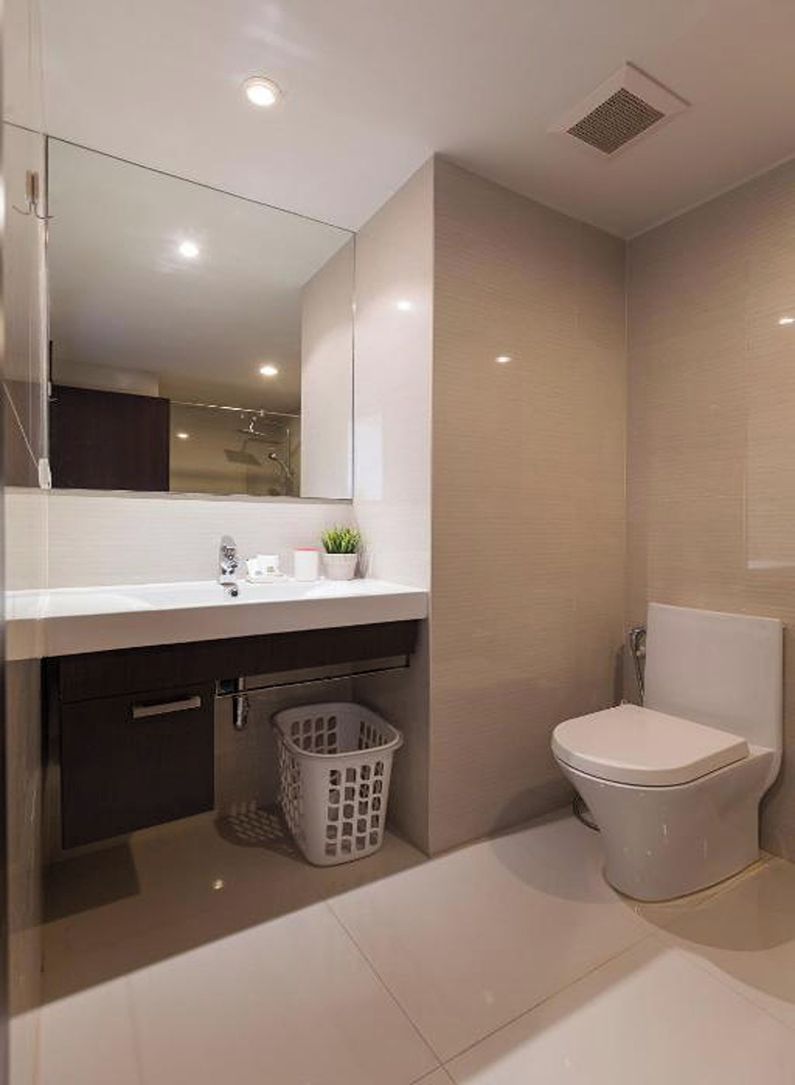 A modern bathroom with a white sink, mirror, and toilet.