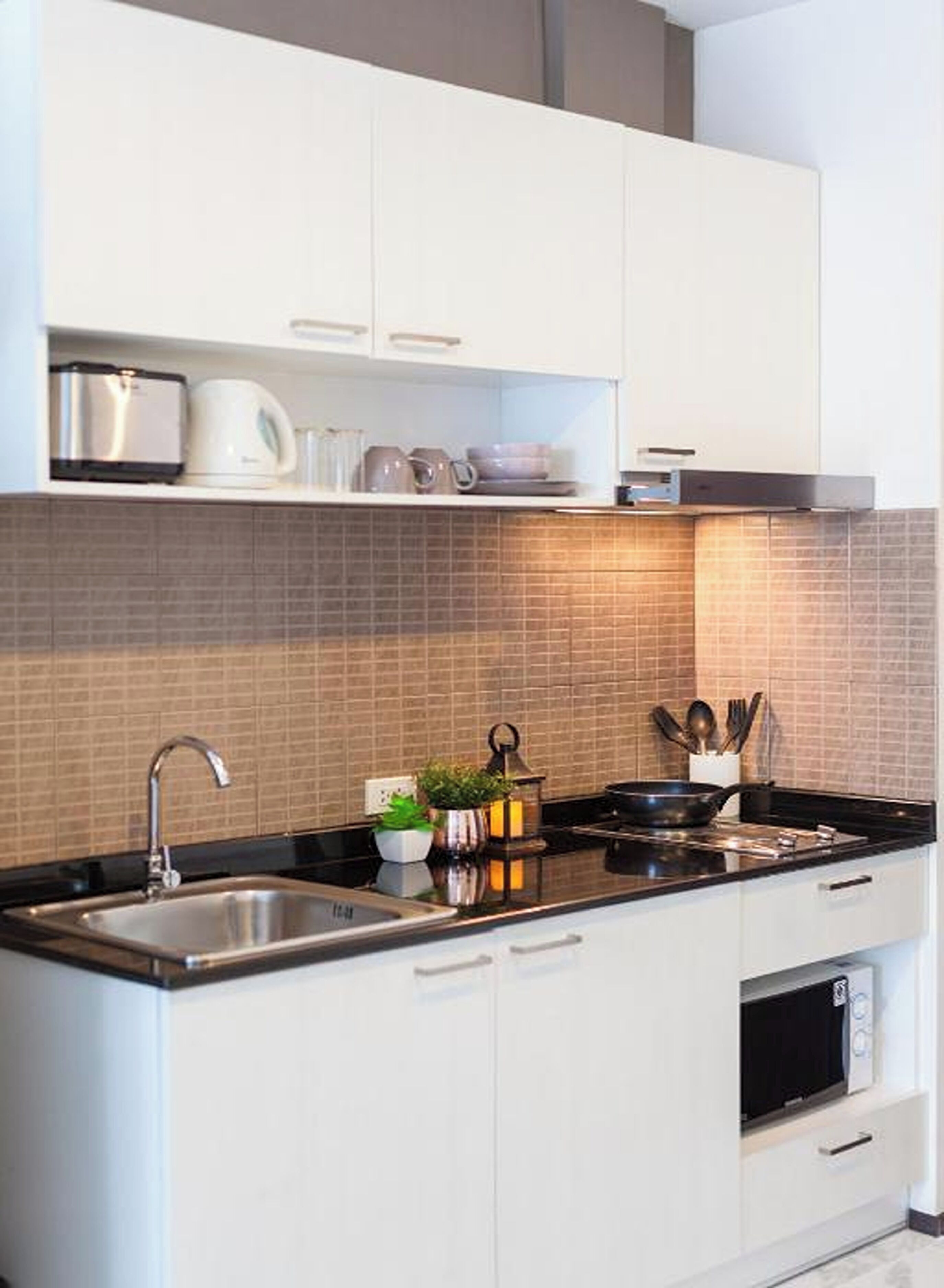A modern kitchen with white cabinets, a black countertop, and a tiled backsplash.