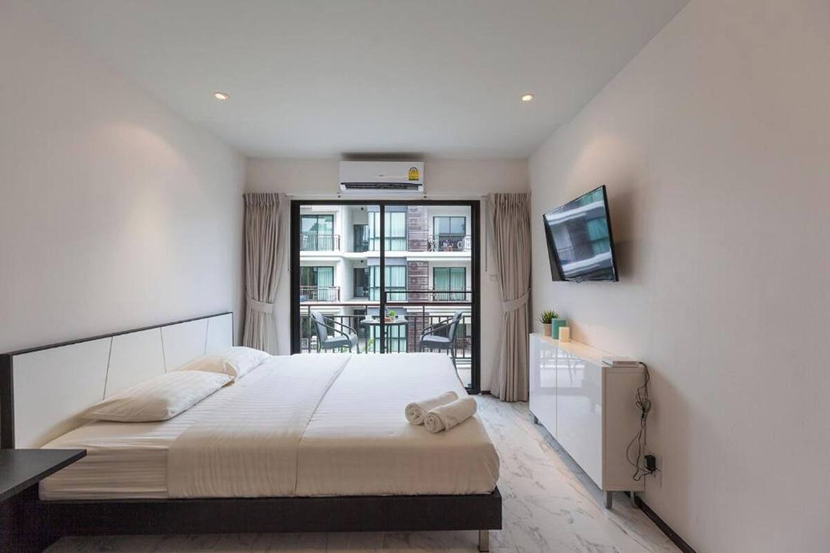 Habitación de hotel con cama, televisión, escritorio y ventana con vistas a edificios.