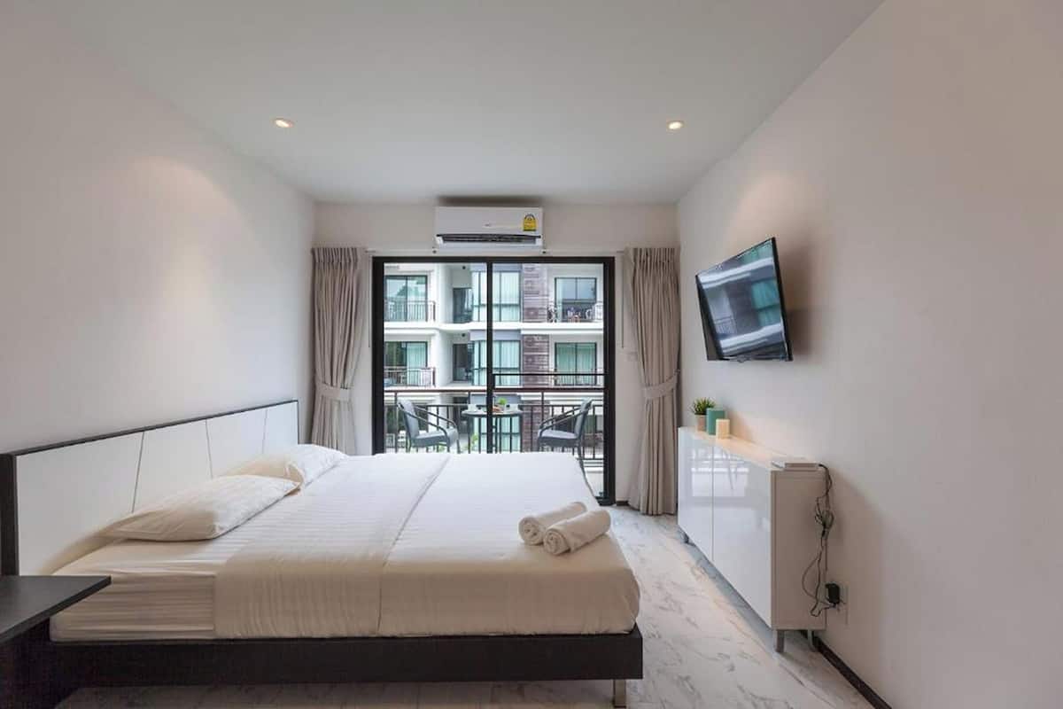 Habitación de hotel con cama, televisión, escritorio y ventana con vistas a edificios.
