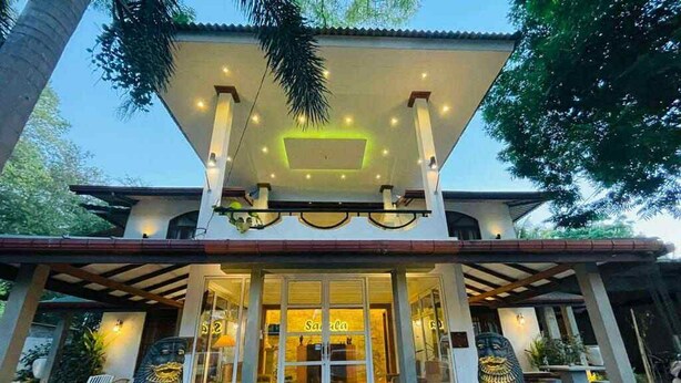 Un edificio moderno con entrada cubierta, ventanas amplias y plantas en macetas.