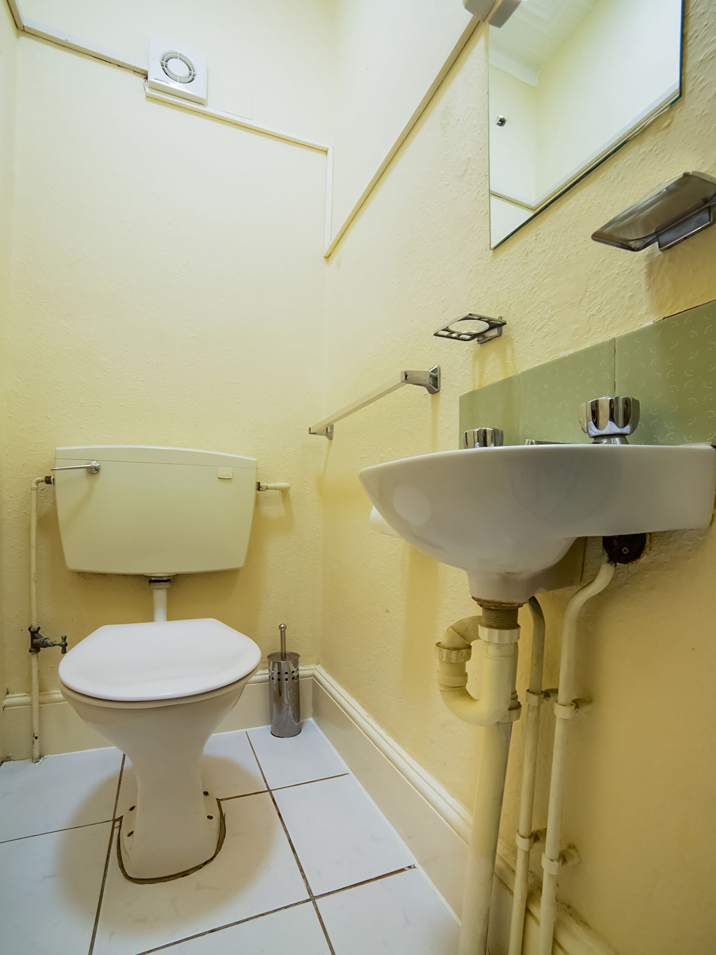 A small, clean bathroom with a toilet, sink, and mirror.