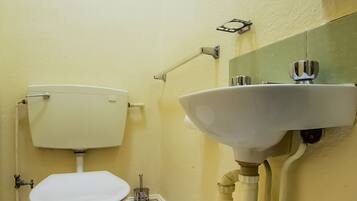 A small, clean bathroom with a toilet, sink, and mirror.