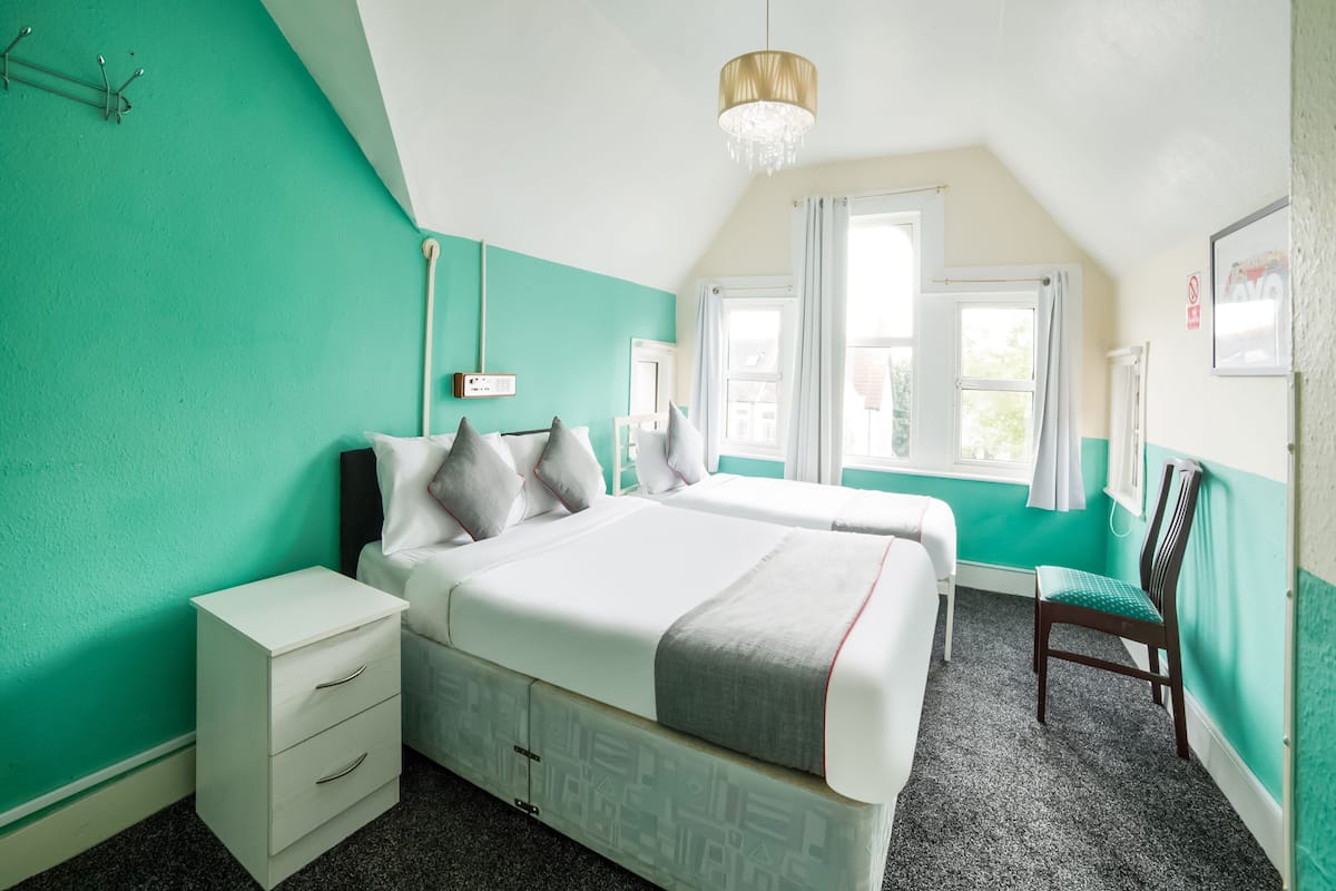 Une chambre à coucher avec un lit, des tables de chevet, une chaise, une fenêtre et un lustre.