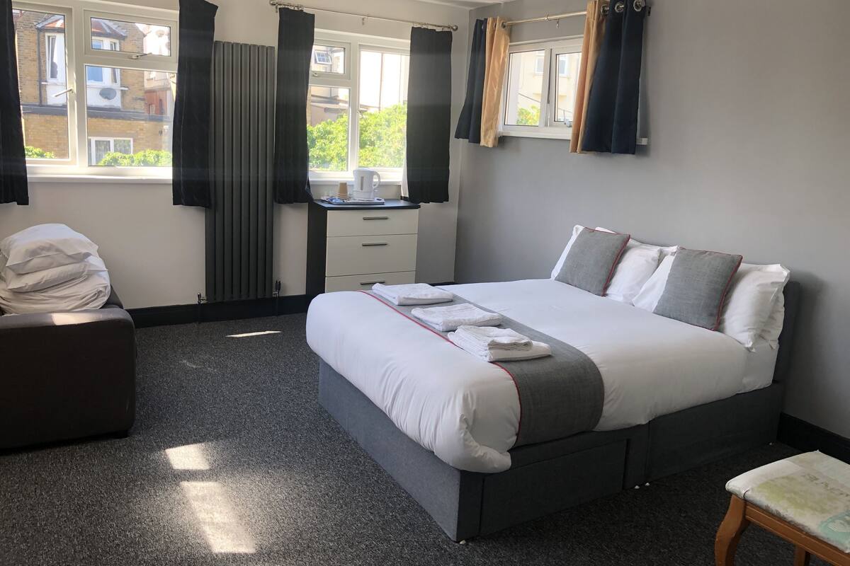 Une chambre d’hôtel avec un lit, un bureau, une chaise et une fenêtre avec des rideaux.