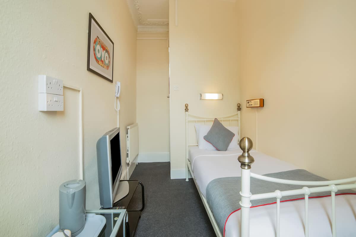 Une chambre d’hôtel équipée d’un lit, d’une table de chevet, d’une télévision et d’un téléphone fixé au mur.