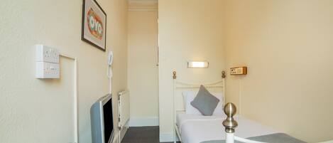 A hotel room with a bed, bedside table, TV, and a wall-mounted phone.