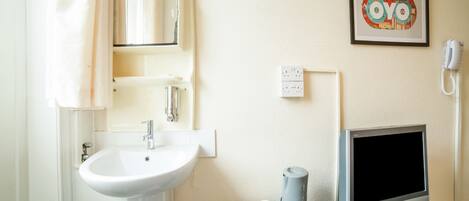 Une salle de bain avec un lavabo, un miroir, une serviette et un tableau encadré au mur.