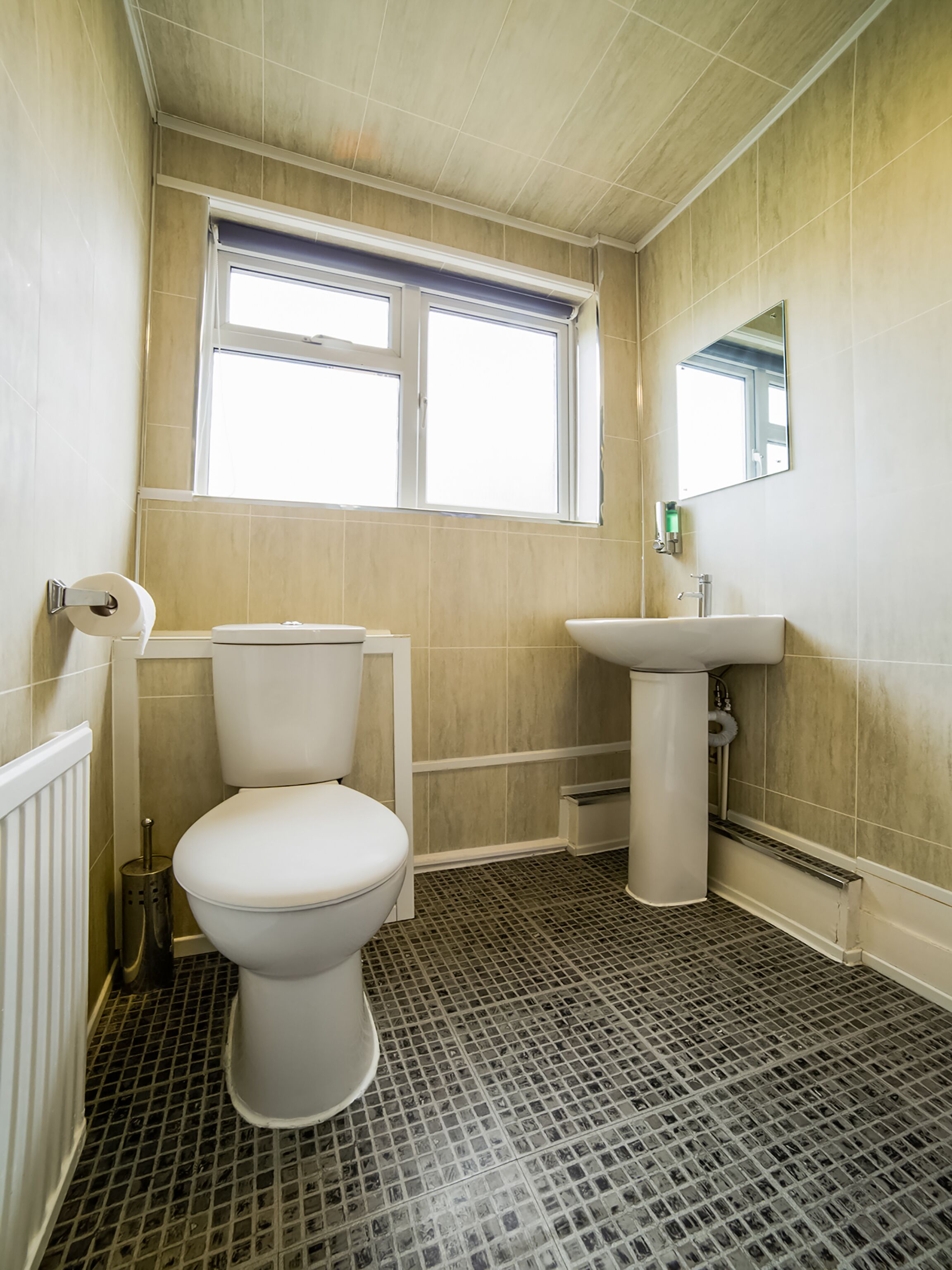 A bathroom with a toilet, sink, and window.
