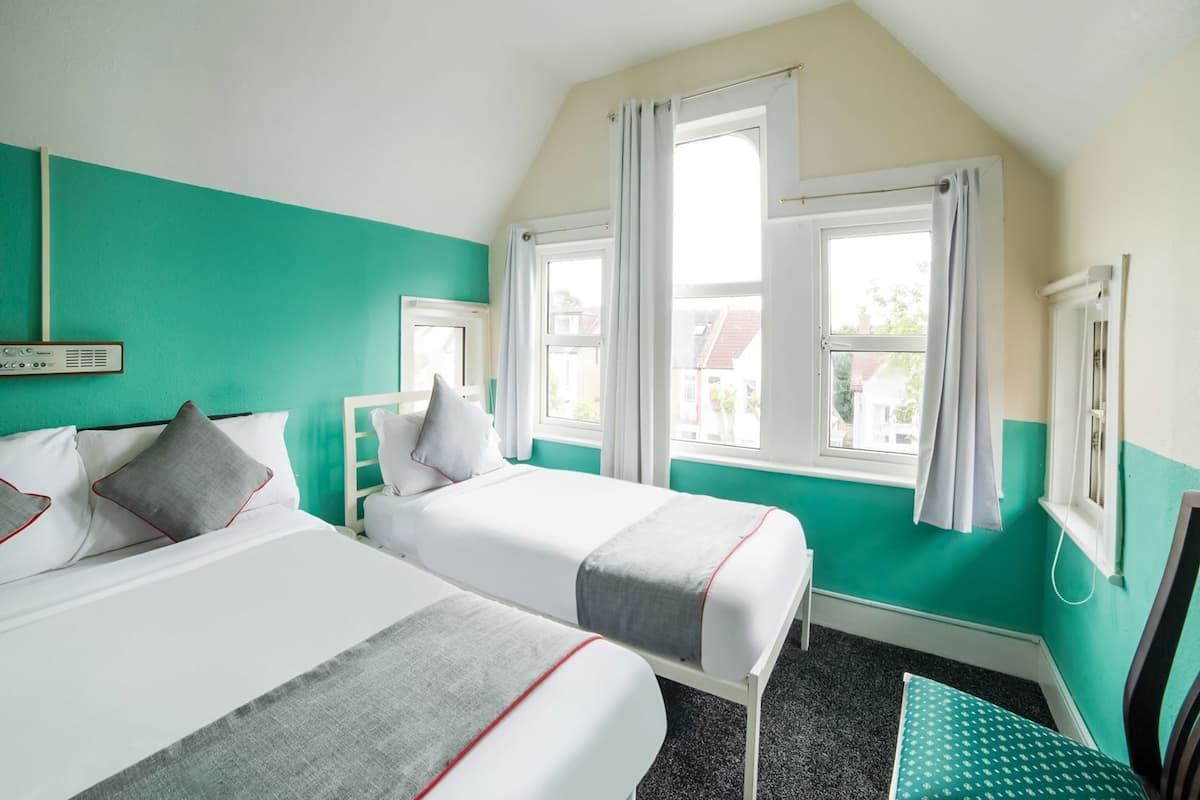 Une chambre avec deux lits, une fenêtre et une chaise.