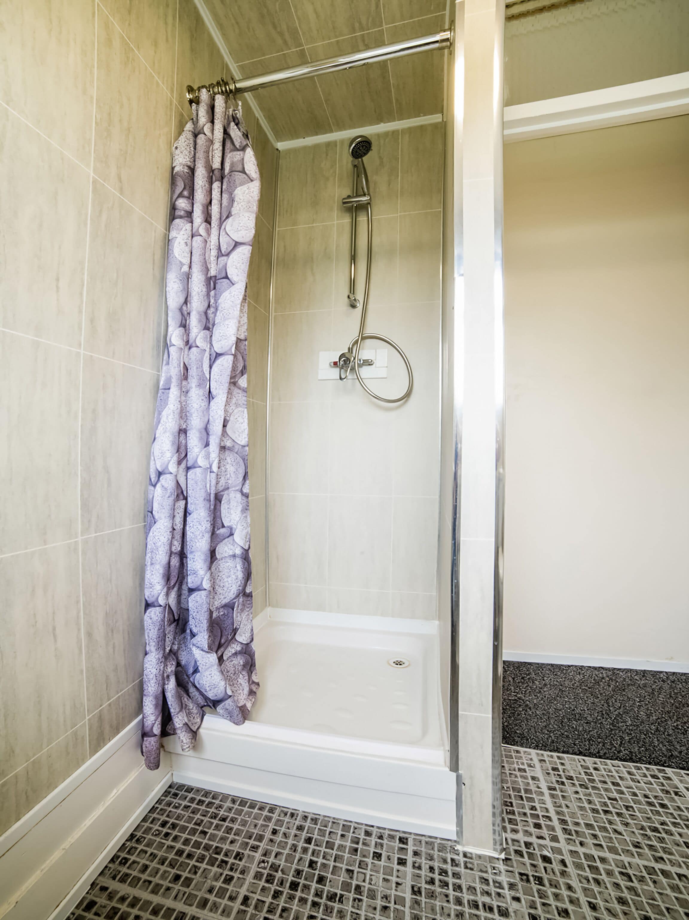 A shower area with a glass door, a showerhead, and a curtain.