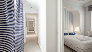 A hotel room with a bed, a view of the hallway, and a striped curtain. - Marina Hotel Charming Rooms (Finale Ligure)