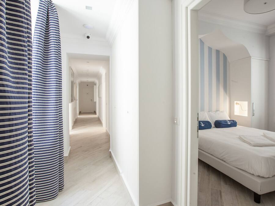 Een hotelkamer met een bed, uitzicht op de gang en een gestreept gordijn.