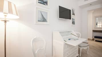 A child's bedroom with a white dresser, a television, and framed pictures on the wall.