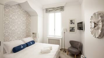 A bedroom with a bed, a chair, a radiator, a window, and wall decorations.