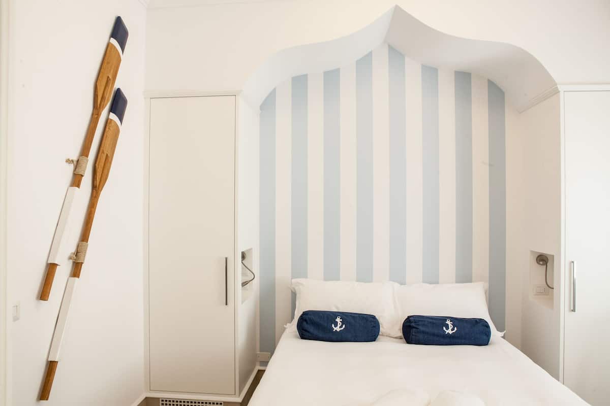 A bedroom with a bed, striped wall, and a door.