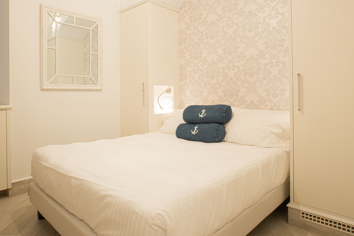 A bedroom with a bed, a mirror, a wardrobe, and a light fixture.