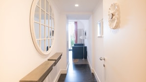 A hallway with a wooden bench, a round mirror, and a decorative wall piece. - Marina Hotel Charming Rooms (Finale Ligure)